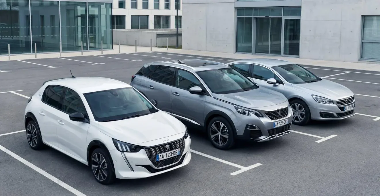 Parking d'agence de location avec trois catégories de véhicules alignés : citadine électrique au premier plan, SUV compact et berline en arrière-plan, dans un environnement extérieur organisé et lumineux